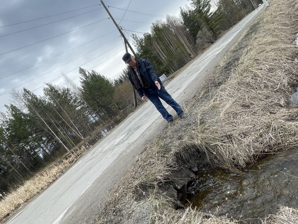 Олег Киселев показал на трубу, которая проложена под автодорогой. По трубе вода стекает в сторону сада. Фото: Анна Куприянова, "Глобус"
